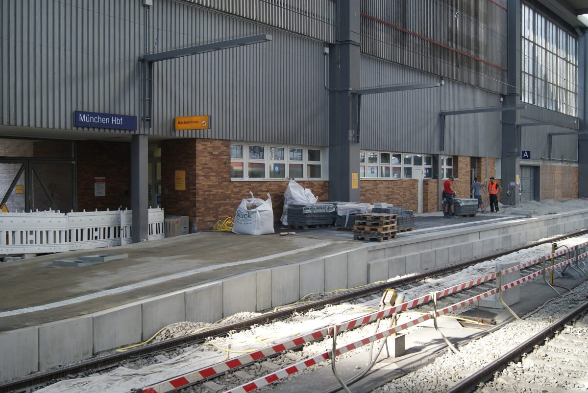 Fachkräfte in Schutzkleidung arbeiten auf dem Abschnitt der Baustelle des Bahngleises, der noch innerhalb des Gebäudes ist.