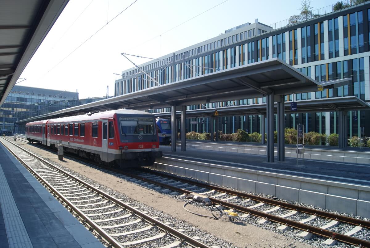 Ein Regionalzug hält an dem verbesserten Bahnsteig. Im Hintergrund sind Münchner Bürogebäude.