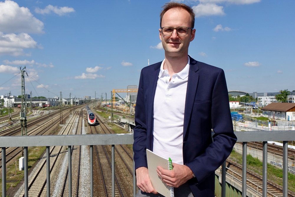 Mathias Beck vor einer Bahnstrecke in München
