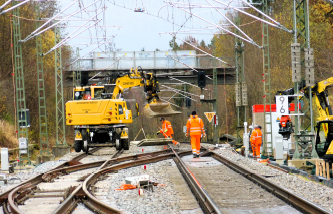 Auf der Baustelle der Überleitstelle Simsee arbeiten Fachkräfte in Schutzkleidung mit Hilfe eines Baggers.