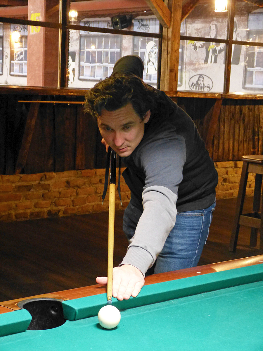 Ein Mitarbeiter spielt die weiße Kugel beim Billiard an.