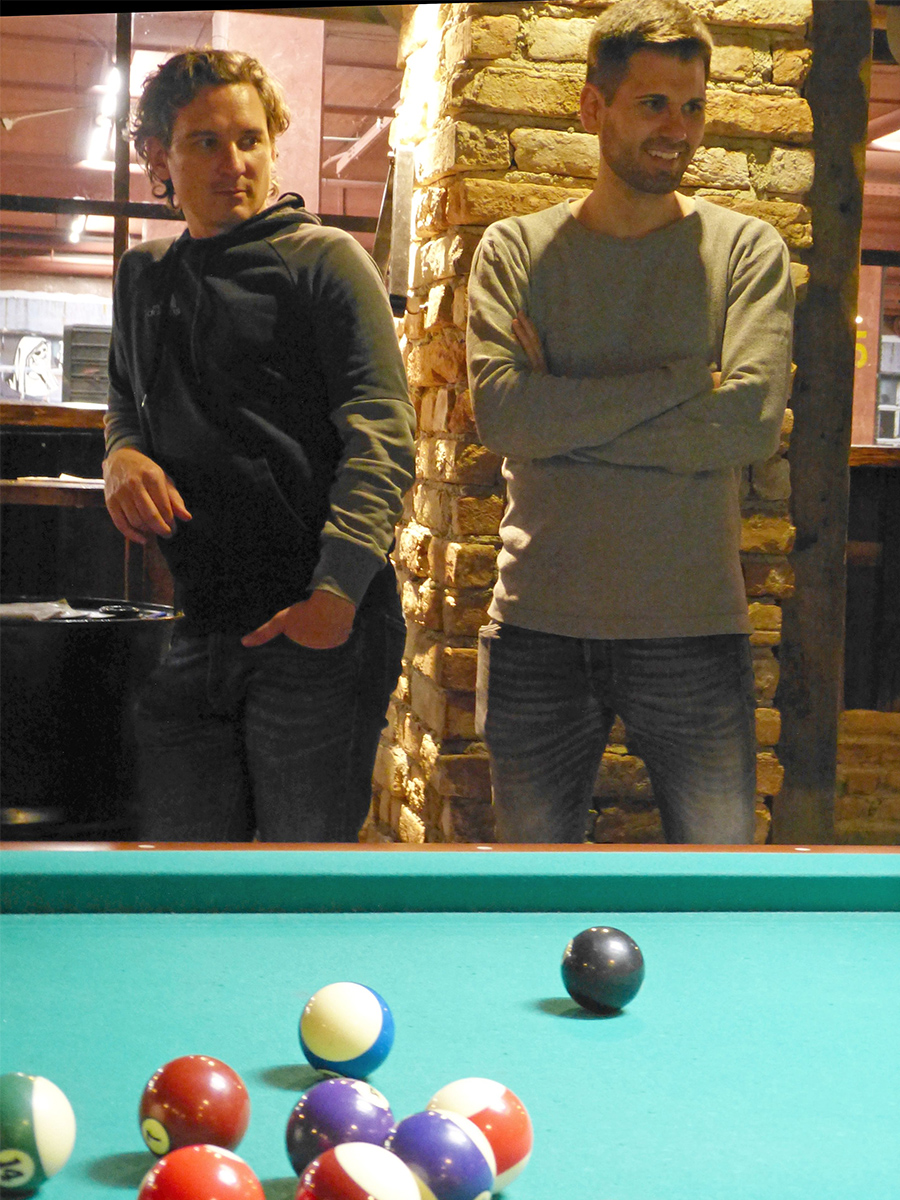 Zwei Mitarbeitende beobachten das Billiard-Spiel.