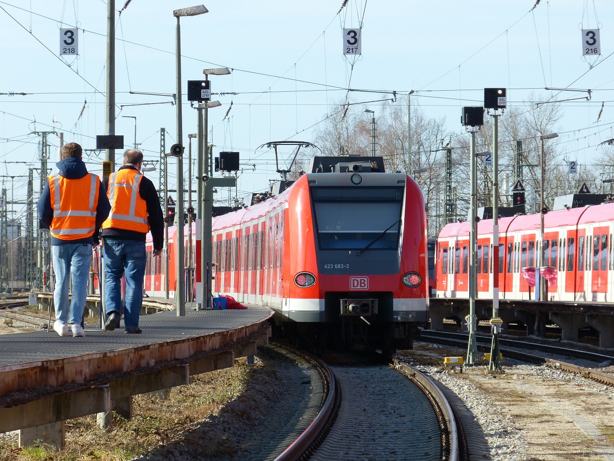 Zwei Mitarbeitende laufen in Schutzkleidung neben einer Strecke entlang.