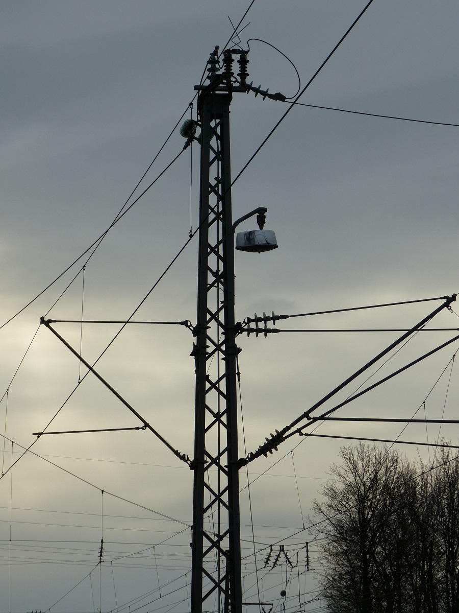 Ein Oberleitungsmast, an den verschiedene Oberleitungen heranführen.