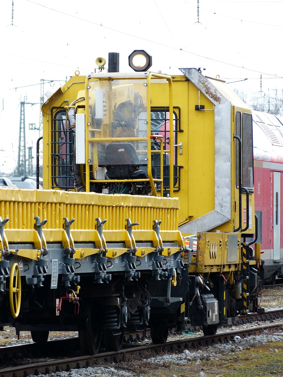 Ein gelber Schienenladewagen fährt auf einer Strecke entlang.