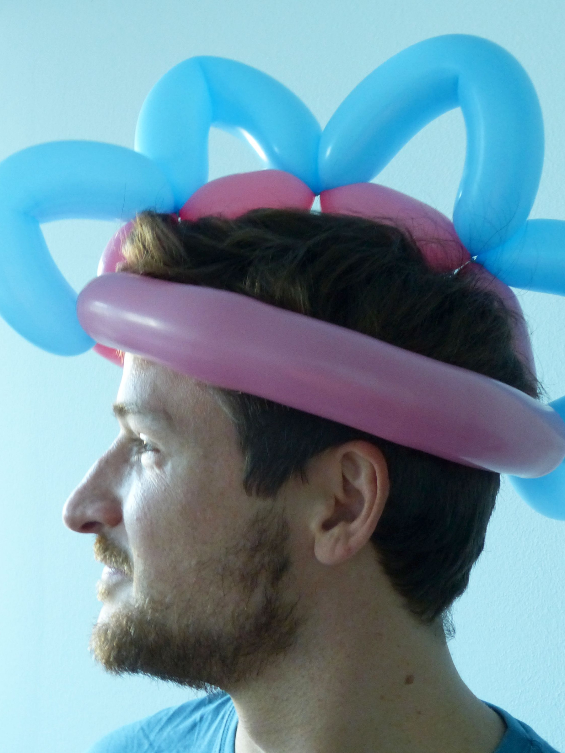 Ein Mitarbeiter trägt einen Hut, der aus Ballons gebastelt wurde.