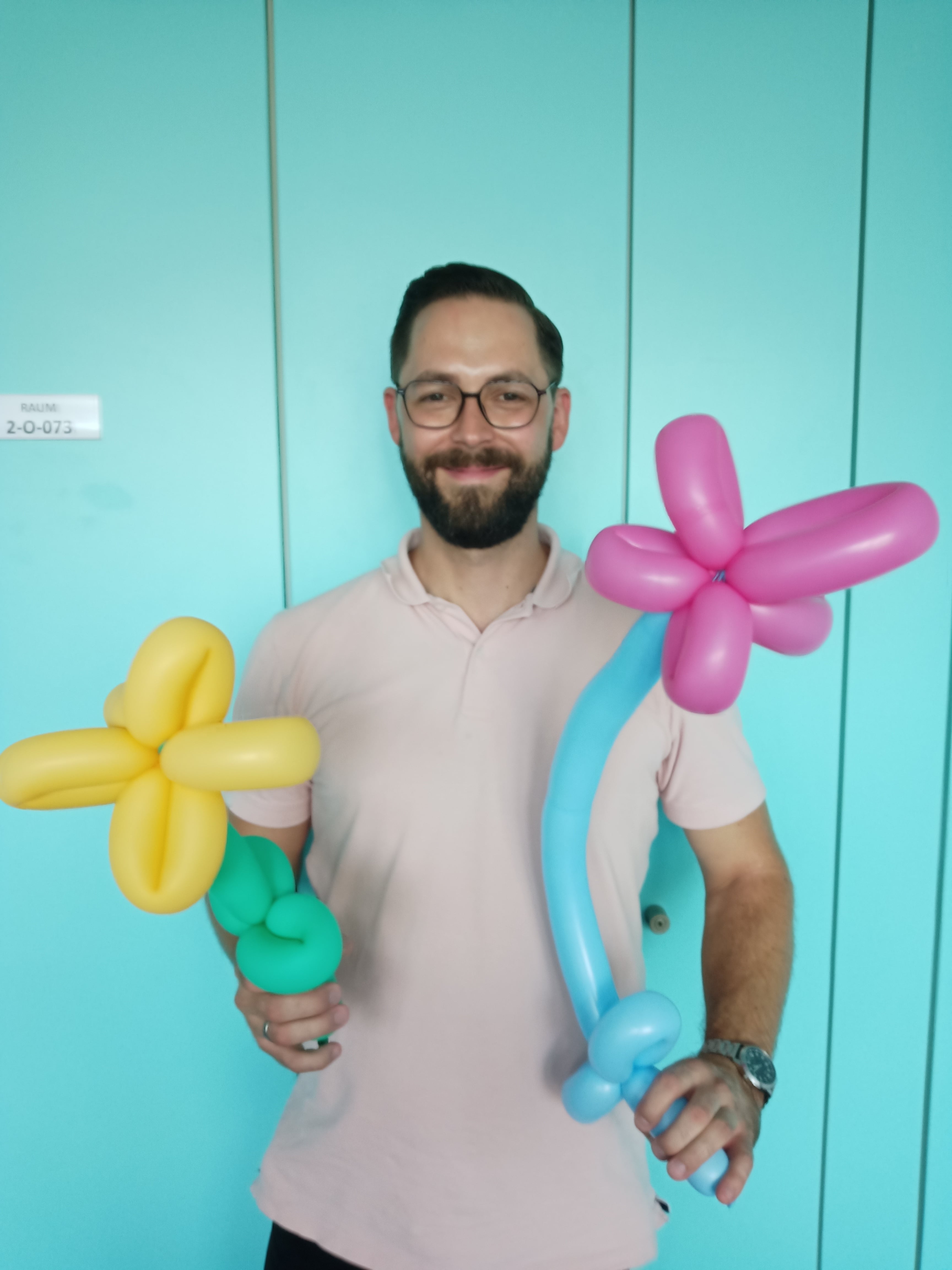 Ein Mitarbeiter hält zwei Ballon-Tier-Blumen in den Händen.