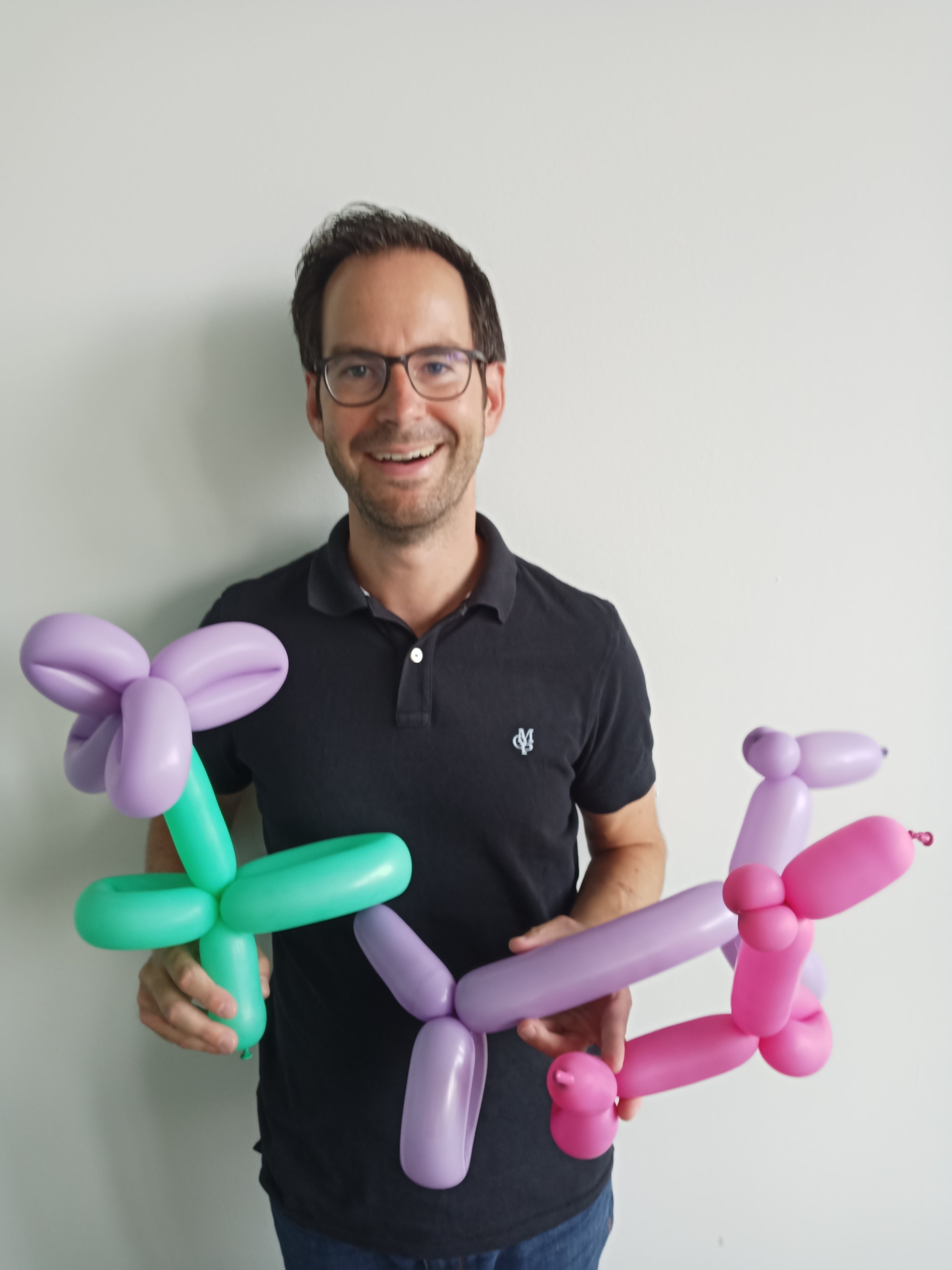 Ein Mitarbeiter mit mehren bunten Ballon-Tieren in den Händen.