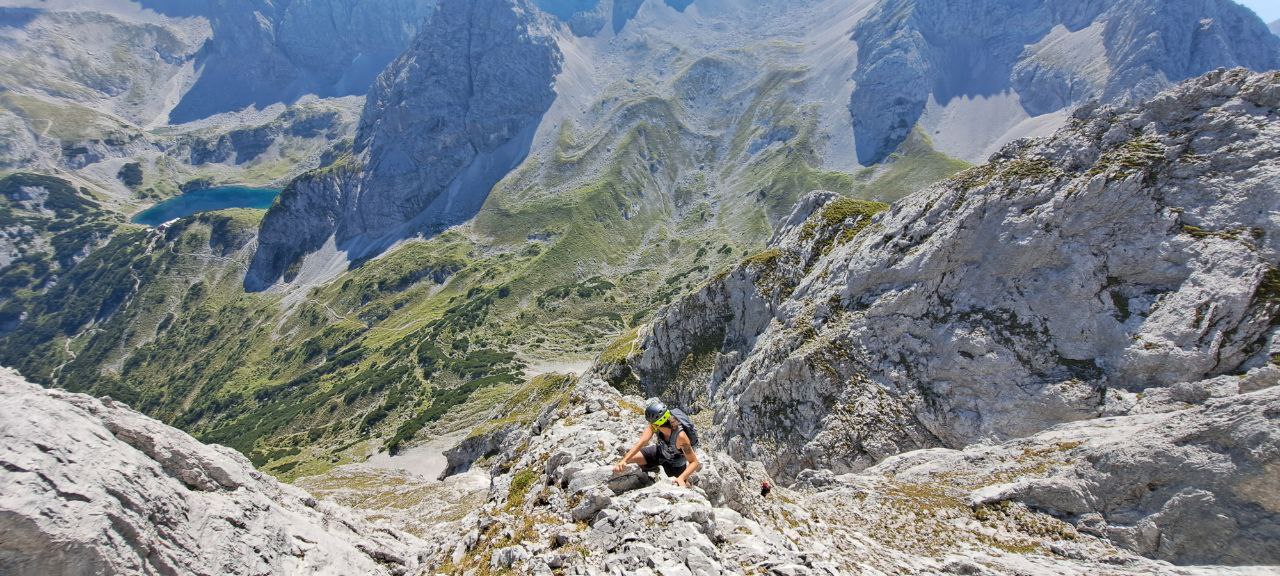 Eine Frau klettert in den Alpen. Sie trägt professionelle Kletterausrüstung.